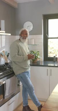 Dikey video: Kıdemli Afro-Amerikan bir adam birini fark ediyor ve sonra akıllı telefonu sayaçla kaydırıyor. Yaşam tarzı, teknoloji, konforlu, çağdaş, sağlık, boş zaman, dikey video