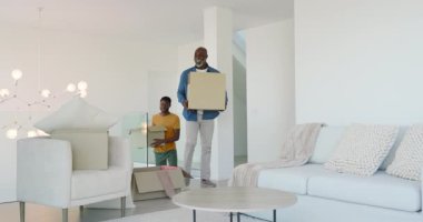 Taşındıktan sonra, Afrikalı Amerikalı baba ve oğul oturma odası için yastıkları ve kutuları açtılar. Aileler, işbirliği, iç mekan, modern, rahat, ev, kaynaşma