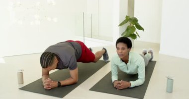 Eğitmen çeşitli antrenman partnerlerine kalas bükme hareketi yaptırıyor, kobra stüdyodaki paspaslar üzerinde geriliyor. Fitness, egzersiz, eğitim, sağlık, uyum.