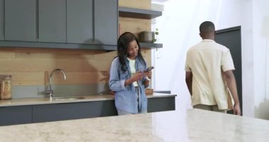 Afro-Amerikalı çift kahverengi market poşetini açmadan önce mermer adaya uzanıp tablet hakkında tartışıyorlar. Romantik, yerli, modern, rahat, yaşam tarzı, teknoloji, aşçılık