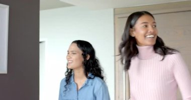 Kadın meslektaşlar mutfakta beyaz çerçeveyi inceliyor, cam tezgah ve dekoratif vazo ile. Minimalist, işbirliği, modern, iç mimari, tasarım, zarafet, takım çalışması