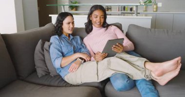 Evdeki gri bölmeli kanepeye bacakları tablet ve kavanozlarla saran farklı kadınları rahatlatıyor. Çağdaş, boş zaman, arkadaşlık, rahat, minimalist, iletişim, yaşam tarzı