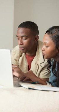 Afro-Amerikan çift yatakta, kalem seçiyorlar ve dizüstü bilgisayardan projelerini gösteriyorlar sonra da beşlik çakıyorlar. İşbirliği, takım çalışması, eğitim, iletişim, teknoloji, samimiyet, dikey video