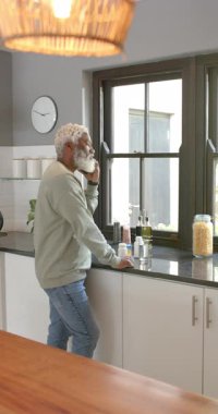 Dikey video: Kıdemli Afrikalı Amerikalı adam tezgah okuyucu şirketinden telefon alıyor. Yaşlılar, sağlık, modern yaşam tarzı, sağlık, iç mekan, dikey video