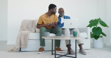 Afrika kökenli Amerikalı baba ve oğul telefonları kaydırıyor sonra da evde babalarına rehberlik ederken dizüstü bilgisayarda yazı yazıyorlar. Aile, akıl hocalığı, teknoloji, bağlantı, yaşam tarzı, modern iletişim
