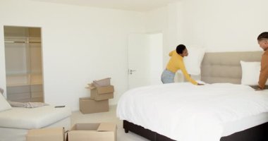 Karton kutuları açan, yastıkları ve kıyafetleri boş yatak odasında ayıran çeşitli çiftler. İşbirliği, takım çalışması, iç mekan, yaşam tarzı, yenileme, organize, minimal