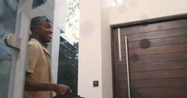 Afro-Amerikalı çift eve tekerlekli bavulla giriyor, ellerinde pasaportlar, kapı açıyorlar. Seyahat, yaşam tarzı, modern, konukseverlik, rahatlık, arkadaşlık, kentsel