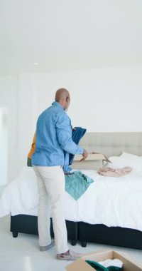 Dikey video: Afrikalı Amerikalı baba ve oğul kutuları açıyor, yatak yapıyor ve yatak odasını hazırlıyorlar. Aile, bağ, aile içi, günlük rutin, iç mekan, işbirliği, dikey video