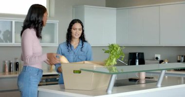 Çeşitli bayan arkadaşlar modern mutfakta telefon ve tereyağlı balkabağı üretiyor. Taze üretim, dostluk, modern iç mekan, sağlıklı yaşam tarzı, aşçılık, işbirliği, canlı