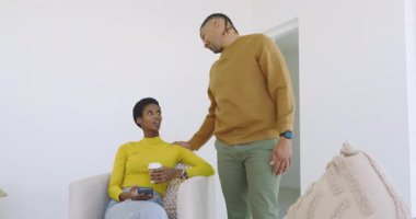 Çeşitli çiftler paketleri boşaltırken yeni evlerinde telefon ve kahve paylaşıyorlar. Yurt içi, yaşam tarzı, samimi, samimi, modern, bağlantı, rahatlama