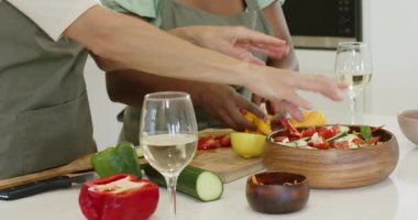 Mutfak adasında çeşitli kadın arkadaşlar, çiseleyen yağ ve salatayı kaseye karıştıran sebzeler görmek. İşbirliği, sağlıklı beslenme, taze üretim, aşçılık, yaşam tarzı, canlı, modern