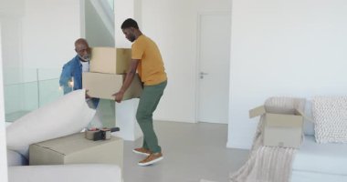 Afro-Amerikalı baba ve oğul kutuları açıyor, molada kanepede kahve içiyor ve içiyorlar. Aile, takım çalışması, aile içi, konukseverlik, rahatlama, samimiyet, çağdaş