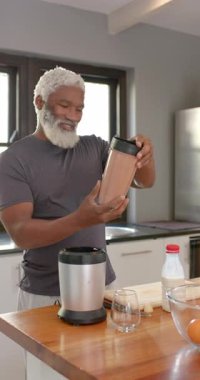 Dikey video: Mutfakta kıdemli Afrikalı Amerikalı adam kavanoz kapağını büküyor, kavanozu sallıyor ve mührü kontrol ediyor. Sağlıklı, sağlıklı, mutfak, yaşam tarzı, modern, beslenme, dikey video