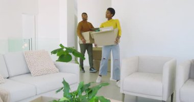 Çeşitli çiftler yeni evlerine yerleşmek için modern oturma odasındaki karton kutuları açıyor. İşbirliği, ev, iç mekan, yaşam tarzı, minimalizm, dekor, takım çalışması