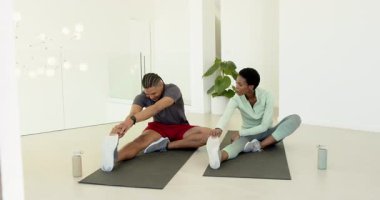 Erkek ve Afrikalı Amerikalı kadın esnekliği artırmak için spor salonunda yoga minderleri üzerinde esnemeye başladılar. Fitness, esneklik, ortaklık, rahatlama, refah, denge, minimalist