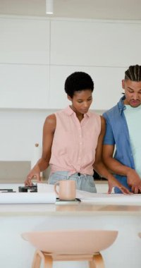 Dikey video: Mutfak adasındaki çeşitli çiftler planı doğrulamak için boyutlarını ayarlıyorlar. İşbirliği, takım çalışması, planlama, mimari, ev yenileme, modern, dikey video