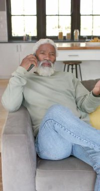 Dikey video: Acil çağrıya cevap veriyorum, evdeki kıdemli adam akıllı telefondan durumu netleştirmek için işaret veriyor. İletişim, konuşma, jest, yüz ifadesi, ev, gündelik, dikey video