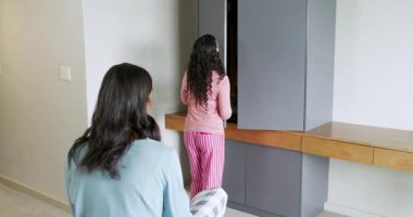 Gri gardırop askıları olan bej rengi pantolonları seçen ev arkadaşlarını tutuyorlar. Yaşam tarzı, moda, iç mekan, günlük, uyum, arkadaşlık, organizasyon