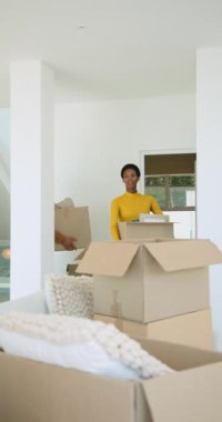 Dikey video: İnişte kutu taşıyan, paketleri açan ve resim çerçevesini inceleyen çeşitli çiftler. Romantizm, yer değiştirme, modern tasarım, yaşam tarzı, samimiyet, ev geliştirme, dikey video