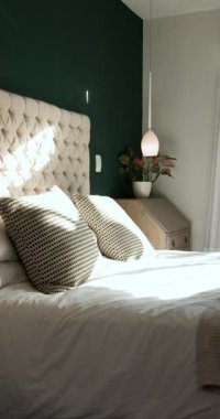 Dikey video: Güneş ışığı düşüyor, kamera yatak başlığından perdelere doğru dönüyor ve pencere manzarasını gösteriyor. Lüks, sükunet, zarafet, dinginlik, modern, minimalist, dikey video