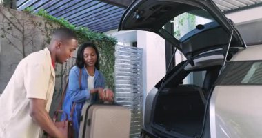 Afro-Amerikalı çift ambar kapağını kaldırırken EV 'yi telefonla şarj ediyor ve pergola altında selfie çekiyorlar. Modern, yaşam tarzı, samimi, açık hava, teknoloji, seyahat, bağlantı