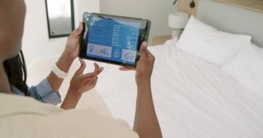 Afrika kökenli Amerikalı çift ellerinde tabletle yatak odasına giriyor, akıllı ev iklimlerini ayarlıyorlar. Teknoloji, yenilik, modern, bağlantı, yaşam tarzı, uyum, ev otomasyonu