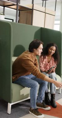 Dikey video: Tablet inceleniyor, çeşitli iş arkadaşları kupayı alıyor ve salonda projeyi tartışıyor. İşbirliği, iletişim, takım çalışması, modern, gündelik, profesyonel, dikey video