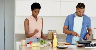 Mutfak adasında sebze doğrarken tavada sebze karıştıran bir çift. Aile içi, aşçılık, minimalist, enerjik, takım çalışması, refah, yaşam tarzı