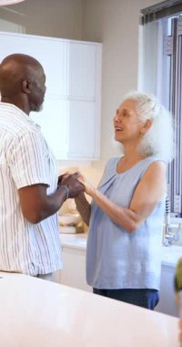 Dikey video: Aşkı gösterdikten sonra mutfak kuvars tezgahında el ele tutuşan yaşlı çift. Sevgi, arkadaşlık, şefkat, bağlantı, sıcaklık, samimiyet, dikey video