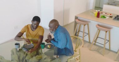 Akıllı telefon almak, Afrika kökenli Amerikalı baba ve oğul masaya oturup telefon görüşmesi yapmak, kahvaltı yapmak. Aile, kaynaşma, eğlence, yerli, samimi, sıradan, modern