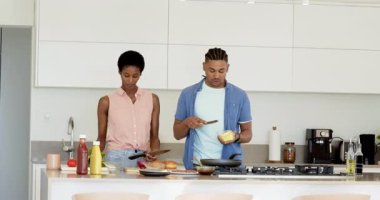 Çeşitli çiftler ekmek dilimliyor ve mutfakta peynirli yumurta pişiriyorlar. Kahvaltı sandviçleri hazırlıyorlar. Aşçılık, takım çalışması, modern, enerjik, yaşam tarzı, beslenme, işbirliği