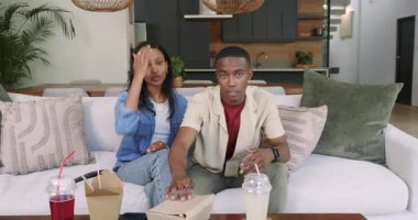 Beyaz kanepeye kurulduktan sonra Afro-Amerikan çift paket yemek yiyor, sarılıyor ve dinleniyor. Romantizm, rahatlık, gündelik, modern, samimiyet, bağlantı, yaşam tarzı