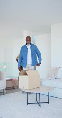 Dikey video: Afro-Amerikalı baba ve oğlu evde resim ve battaniye yerleştirerek kutularını açıyor. Aile, taşınma, işbirliği, modern, ev, bağ, dikey video