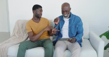 Afro-Amerikalı baba ve genç oğul evde tablet tıkırdatıyor, el sıkışıyorlar ve yeşil kupayı yudumluyorlar. Aile, akıl hocalığı, bağlantı, teknoloji, rahatlama, sıcaklık, bağ