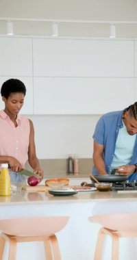 Dikey video: Kahvaltı için çeşitli çiftler mutfakta soğan çırpma çırpma yumurtaları katlayarak omlet yapıyor. Aşçılık, aşçılık, modern, yaşam tarzı, hazırlık, yerli, dikey video