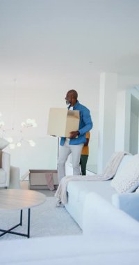 Dikey video: Evde eğilme, Afrikalı Amerikalı baba ve oğlu avizenin altına kutular koyuyor. Kutlama, takım çalışması, aile, ev, modern, rahat, dikey video