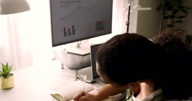 Not defterine bakıyorum, kadın monitör çizelgelerini işaretliyor ve masadaki karalama sonuçları, kopyalama alanı. Yenilik, analiz, veri, çalışma alanı, teknoloji, profesyonellik, üretkenlik