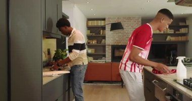 Akşam yemeğini bitirdikten sonra, çeşitli erkek arkadaşlar bulaşıkları yıkıyor ve modern mutfakta tezgahı siliyorlar. İşbirliği, ev işi, yerli, takım çalışması, modern, enerjik, yaşam tarzı