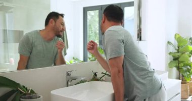 Asyalı bir erkek banyo lavabosunda su sıçratıyor, sabah bakım için deri kavanozundan maske takıyor. Cilt bakımı, hijyen, tazelik, minimalizm, rahatlama, sağlık.