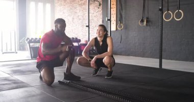 Çeşitli arkadaşlar yorgunluk işaretini fark edip kalçalarında masaj tabancası ve spor salonunda su içiyorlar. Fitness, rehabilitasyon, takım çalışması, sağlık, motivasyon, güç, rahatlama