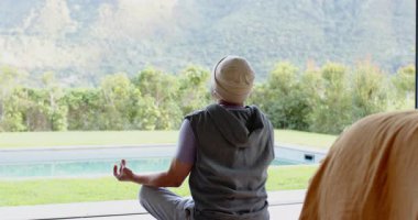 Olgun bir Asyalı adam meditasyon yapıyor ve esneklik için kollarını yoga minderinin üstüne koyuyor. Zen, rahatlama, açık hava, güneş ışığı, sağlık, sükunet, doğa.