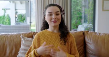 Kameraya çekiliyor, 20 'li yaşlarda bir kadın evdeki deri koltukta el kol hareketi yapıyor ve mesajını paylaşıyor. İletişim, hikaye anlatımı, bağlılık, yaşam tarzı, modern, otantik, anlamlı