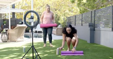 Arka bahçeye giren çeşitli kadın sunucular ellerinde şişelerle halkaların ışığını hazırlayıp egzersiz yaptırıyorlar. Fitness, collaboration, outdoor, wellness, modern, lifestyle, activity