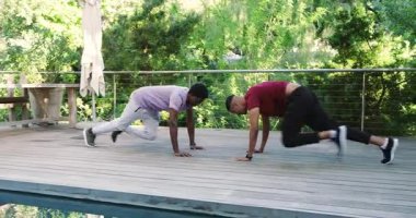 Çeşitli erkek arkadaşlar havuz güvertesinde tahta döşemeye başlıyorlar. Dağcılar tırmanıyor sonra da el sıkışarak şınav çekiyorlar. Fitness, yoldaşlık, atletizm, açık hava, aktif giyim, sağlık, arkadaşlık