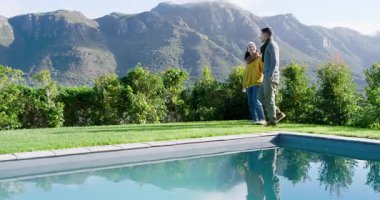 Bir çift havuz kenarında yürürken dağları işaret ediyor, durup bakıyor ve sohbet ediyorlar. Açık hava, boş zaman, manzara, manzara, dinginlik, rahatlama, doğa.