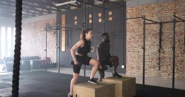 Çeşitli antrenman partnerleri spor salonundaki dambıllarla plyo kutularının üzerinde sırayla adım atıyorlar. Fitness, strength, training, fonksiyonel, dayanıklılık, motivasyon, atletizm