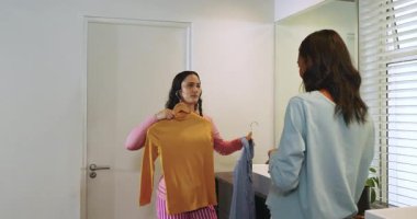 Banyoda lavabonun üzerinde asılı hardal sarısı elbise ve açık mavi bluz, renk kontrastı gösteriyor. Bariyersiz, minimalizm, moda, iç mekan, tarz, zarafet, ev yapımı