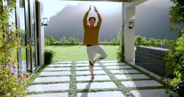 Asyalı erkek, pergola 'nın altındaki taş şebekede hareketsiz duruyor denge için kollarını ağaç pozisyonuna kaldırıyor. Farkındalık, sağlık, dinginlik, doğa, uyum, açık hava, yaşam tarzı