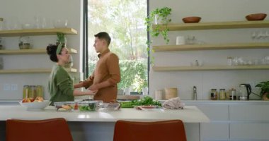 Dönen, kucaklayan, mutfak adasında güneş camdan içeri girerken kâselerle öpüşen çiftler. Romantizm, şefkat, yakınlık, yaşam tarzı, modern, neşeli, sıcak