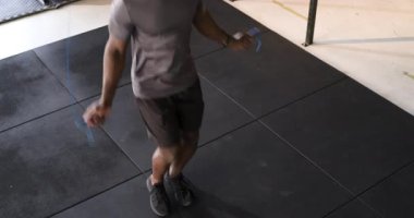 Mavi saplı atlama halatı ve paspasın üzerinde zıplamak. Formda adam spor salonunda kardiyo ritmini koruyor. Fitness, dayanıklılık, momentum, güç, çeviklik, eğitim, aktif giyim